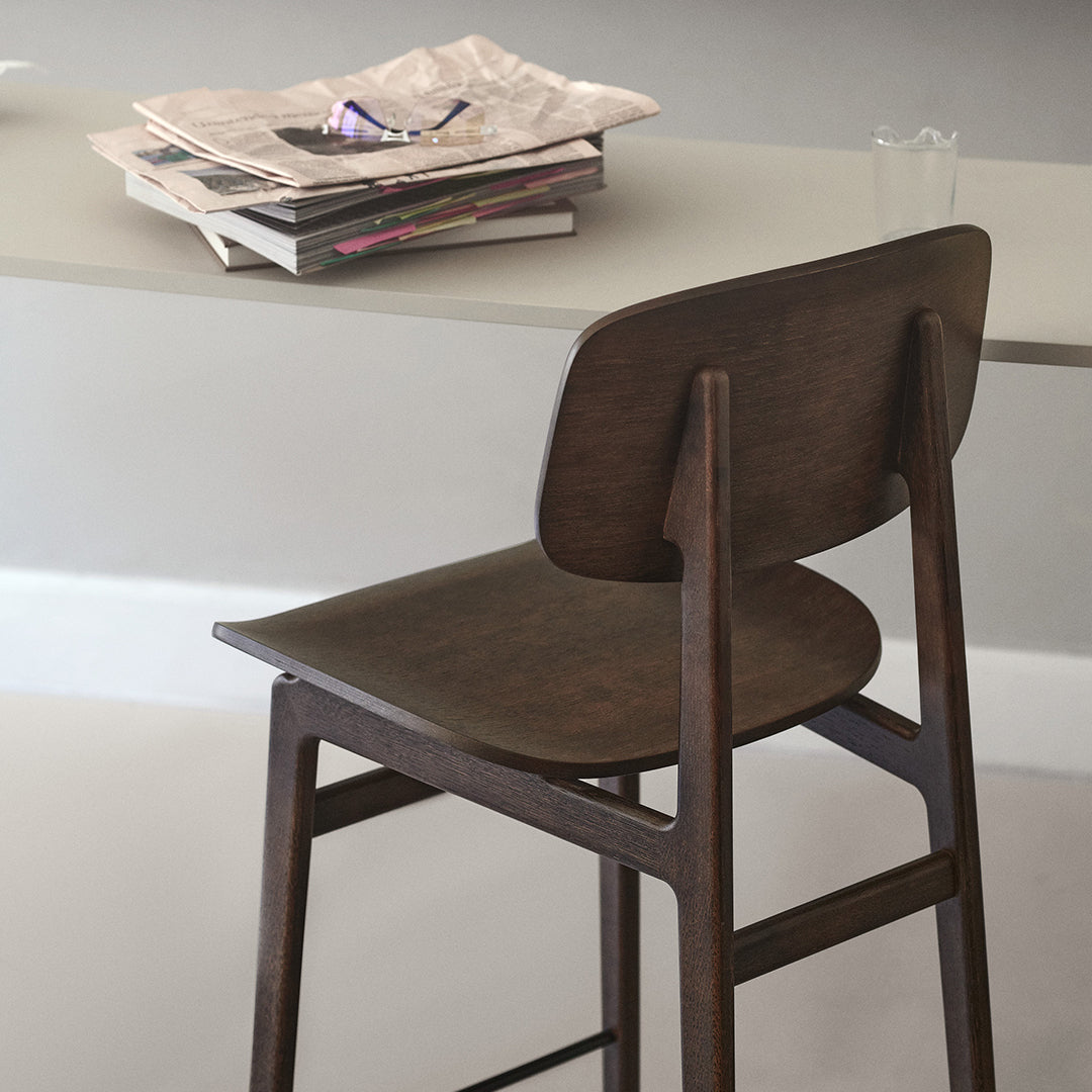 Dark wooden chair with smooth, minimalist design against a light gray table. Elegant, modern aesthetic.