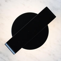 Black circular surface with a sleek black bar overlay, featuring a minimalist design ideal for modern decor.