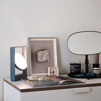 Stylish blue lamp with a circular white shade, paired with a minimalist black and white decor and various modern accessories.