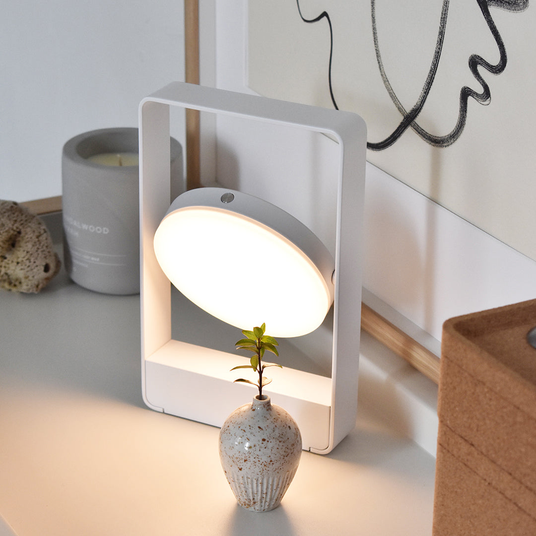 Sleek white lamp with an oval light, set against a minimalist background featuring neutral tones.