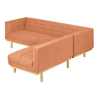 "Modern L-shaped sofa in soft terracotta with a textured fabric and natural wood legs."