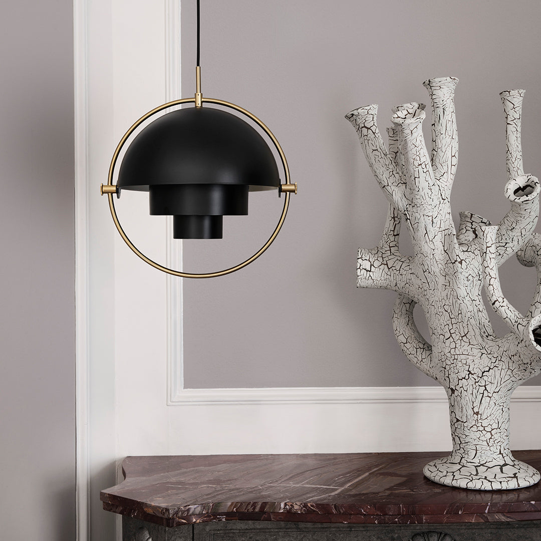 Black pendant light with gold accents, featuring a sleek circular design against a neutral wall backdrop.