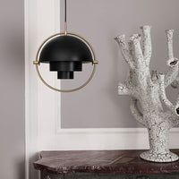 Black pendant light with gold accents, featuring a sleek circular design against a neutral wall backdrop.