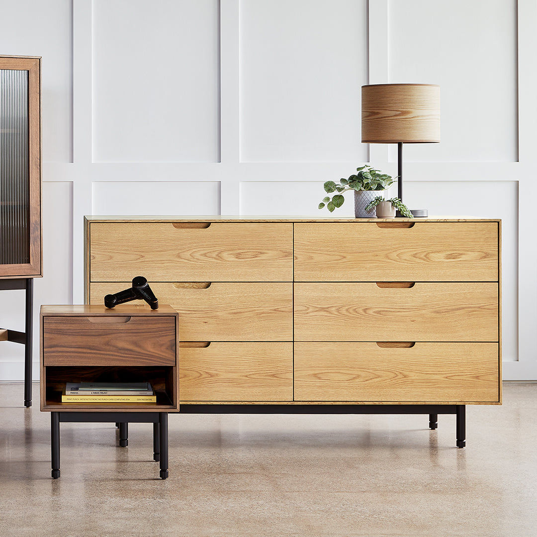 Light wood dresser with six drawers, modern black legs, and a matching nightstand in a natural wood finish.