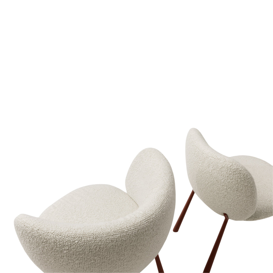 White boucle fabric chairs with smooth, rounded shapes and minimalist wooden legs, elegantly showcasing texture and modern design.