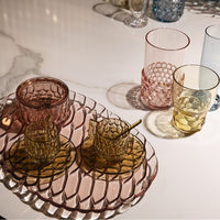 "Elegant glassware set featuring pink and amber hues with textured honeycomb patterns on a stylish tray."