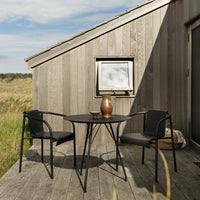 Stylish black metal outdoor table and chairs with a smooth finish against a rustic wooden backdrop.