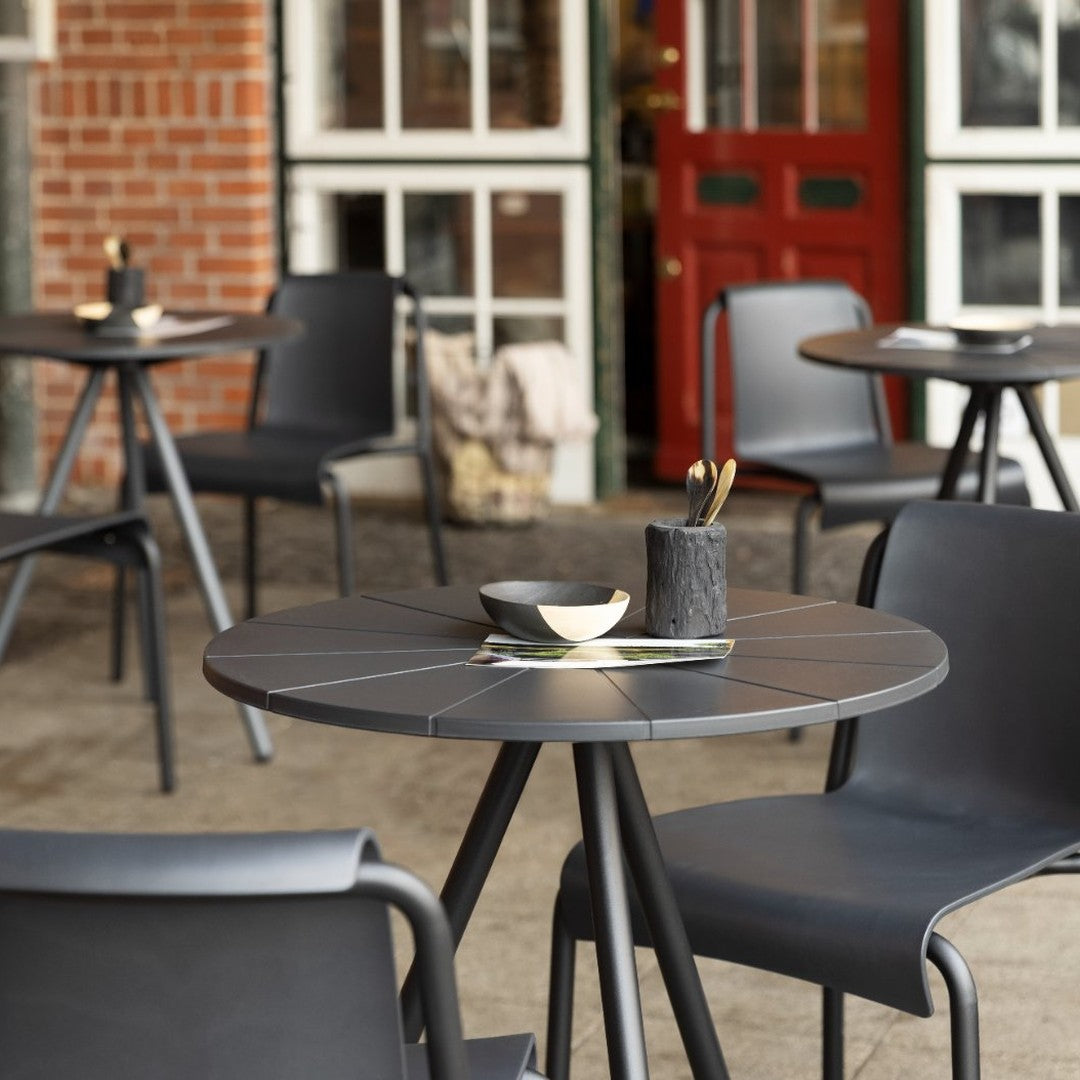 Contemporary black outdoor dining set with sleek lines and minimalist design, featuring a round table and stackable chairs.