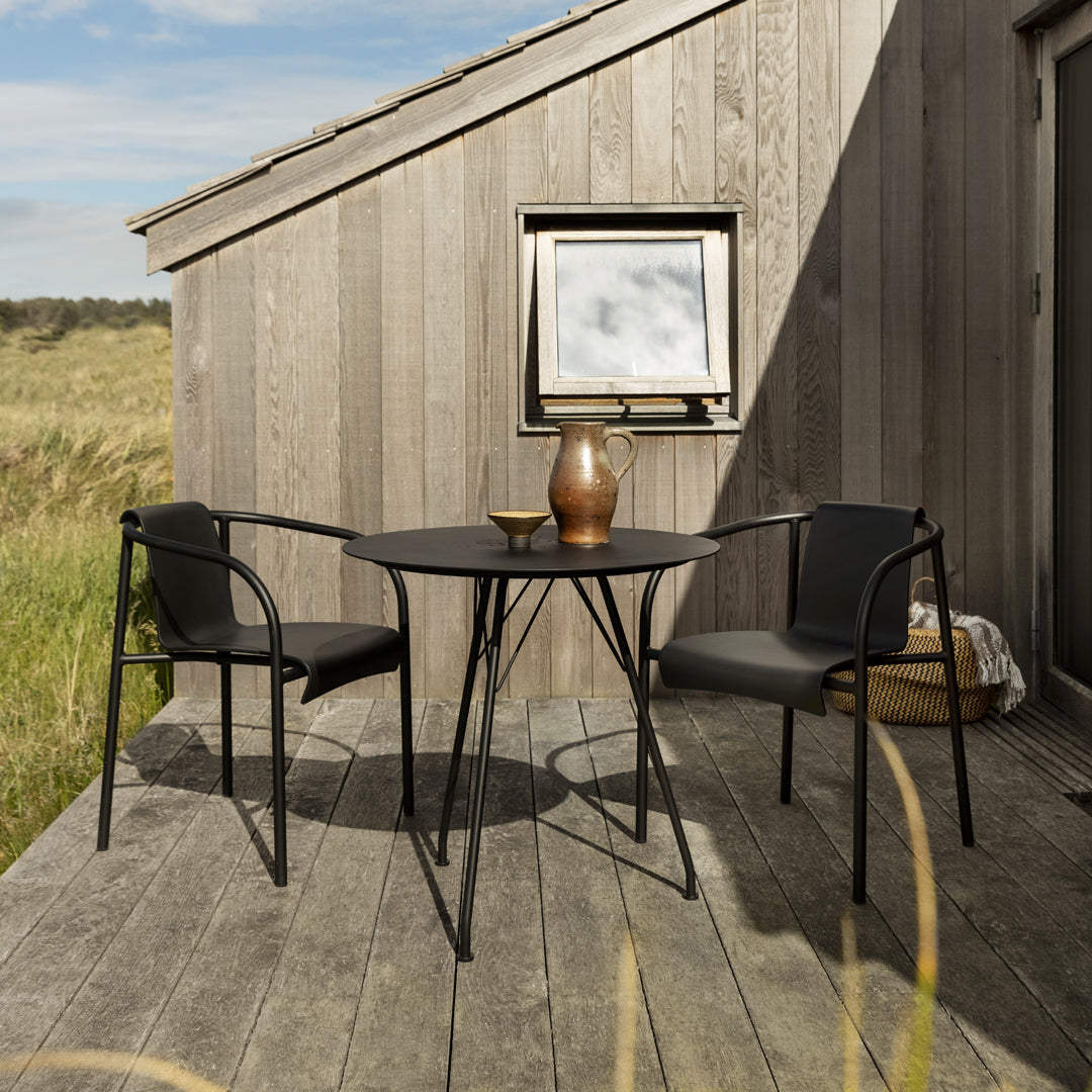 Stylish black metal outdoor table and chairs with a smooth finish against a rustic wooden backdrop.