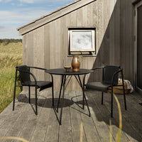 Stylish black metal outdoor table and chairs with a smooth finish against a rustic wooden backdrop.