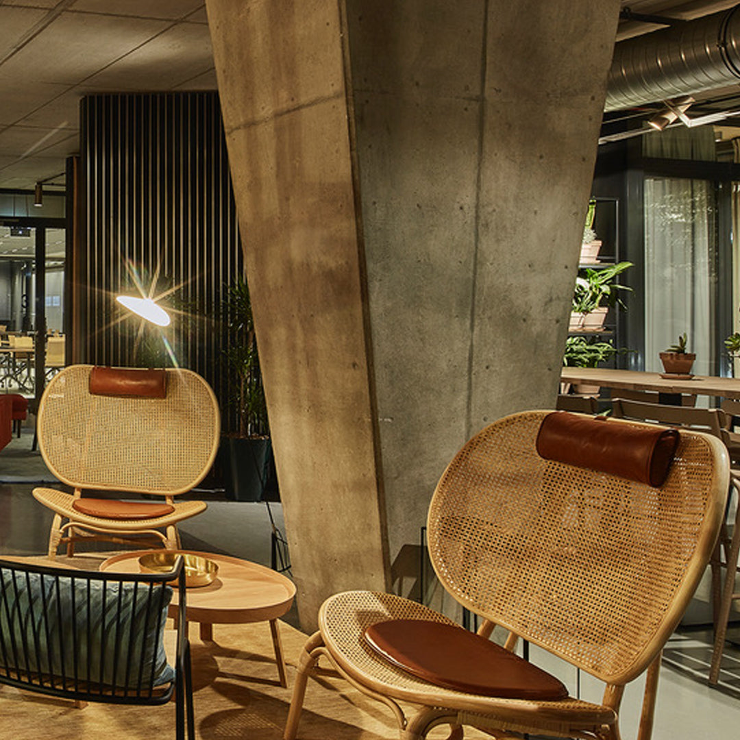 "Natural rattan chairs with brown leather accents, complemented by a modern industrial backdrop."
