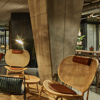 "Natural rattan chairs with brown leather accents, complemented by a modern industrial backdrop."