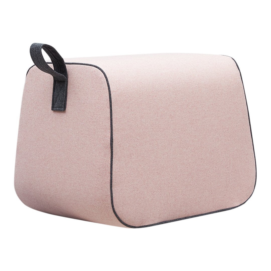 Soft pink accent pouf with a textured finish and contrasting black edges. Ideal for modern decor.