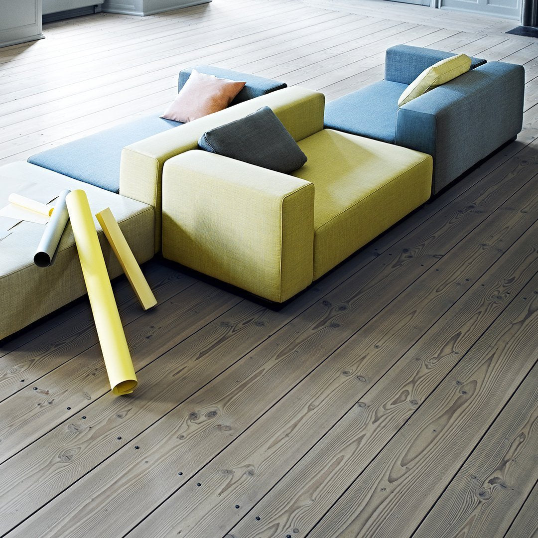 Colorful modular sofa in yellow, blue, and gray, with scattered yellow tubes on wooden floor.
