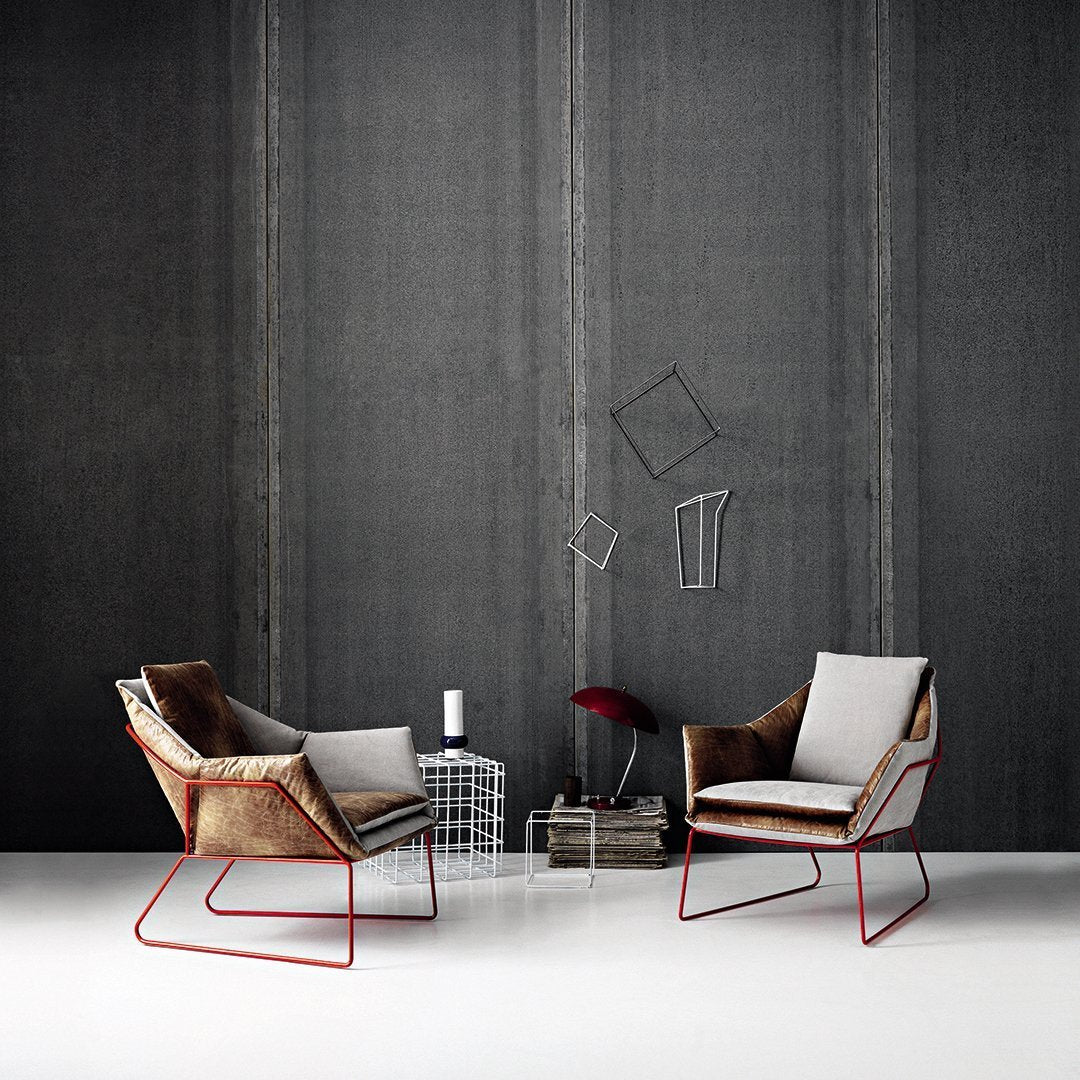 Modern chairs featuring neutral fabric with a textured brown pattern and sleek red metal legs against a gray backdrop.