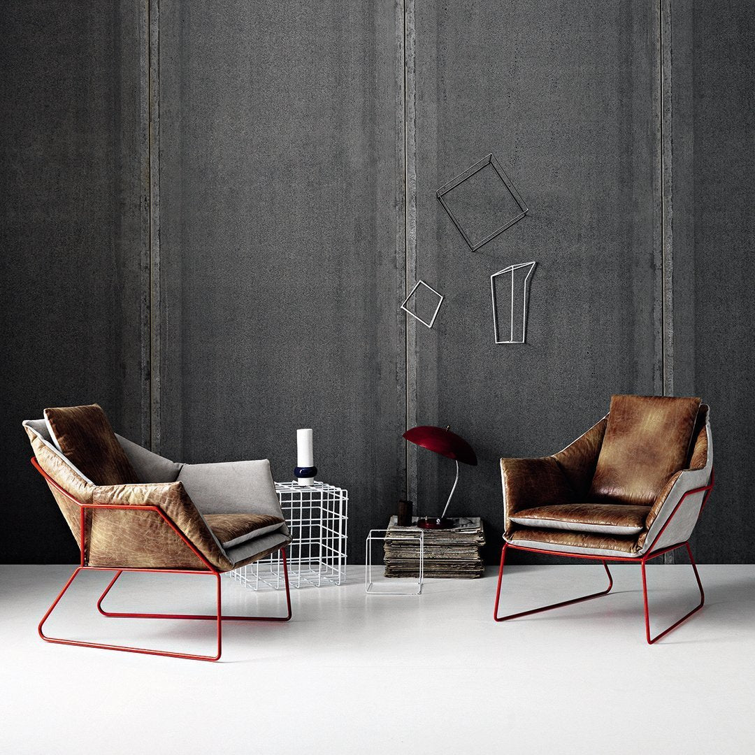 Two modern armchairs in a mix of soft gray and warm brown textures, featuring sleek red metal frames.
