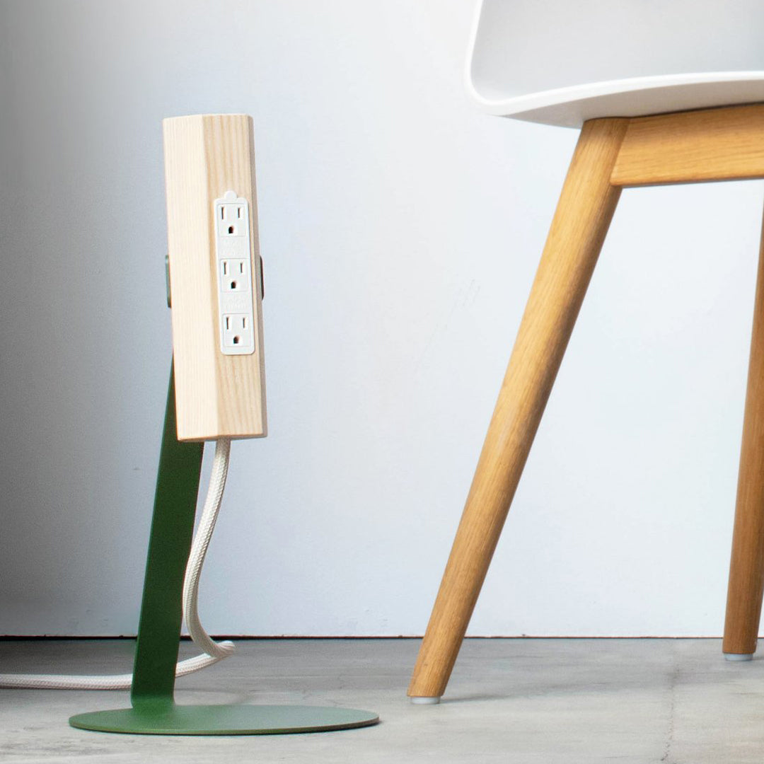 Modern power strip with a light wood finish and green accent, set against a minimalist background.