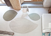 Textured area rugs in soft green and neutral tones, featuring leaf-inspired patterns. Perfect for modern decor.