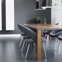 Modern dining table with a rich wooden top, paired with sleek gray chairs against a minimalist monochrome backdrop.