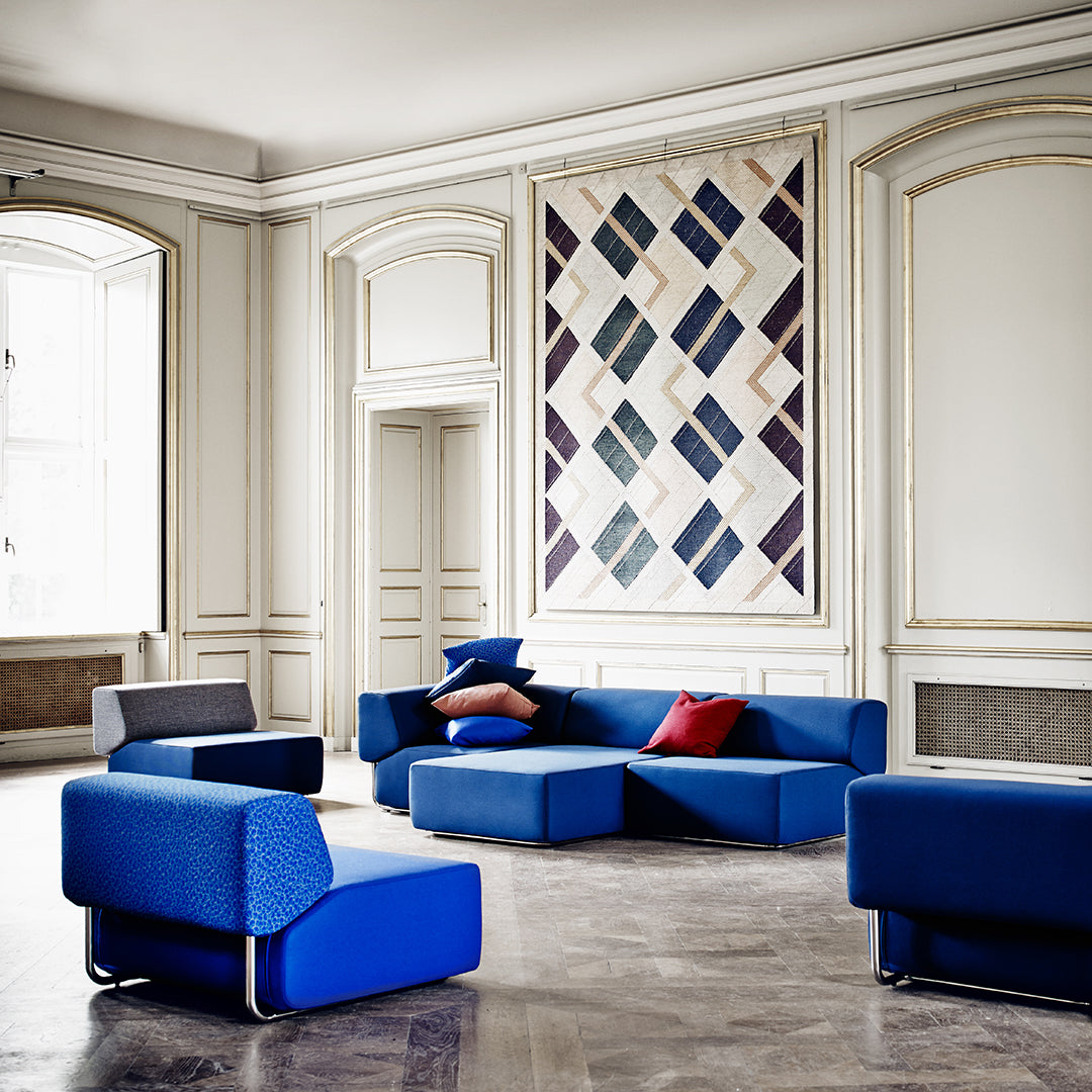 "Contemporary furniture in vibrant blue with geometric patterns, accented by red and purple pillows."