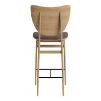 Light wood bar stool with a curved back, featuring a dark cushioned seat and a sleek black metal footrest.