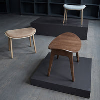 Three stylish chairs with natural wood textures: light beige, rich brown, and smooth white, displayed on dark stands.