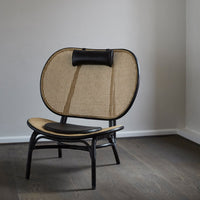 Natural rattan chair with a curved black frame and woven beige seat, featuring a minimalist design and modern decor appeal.