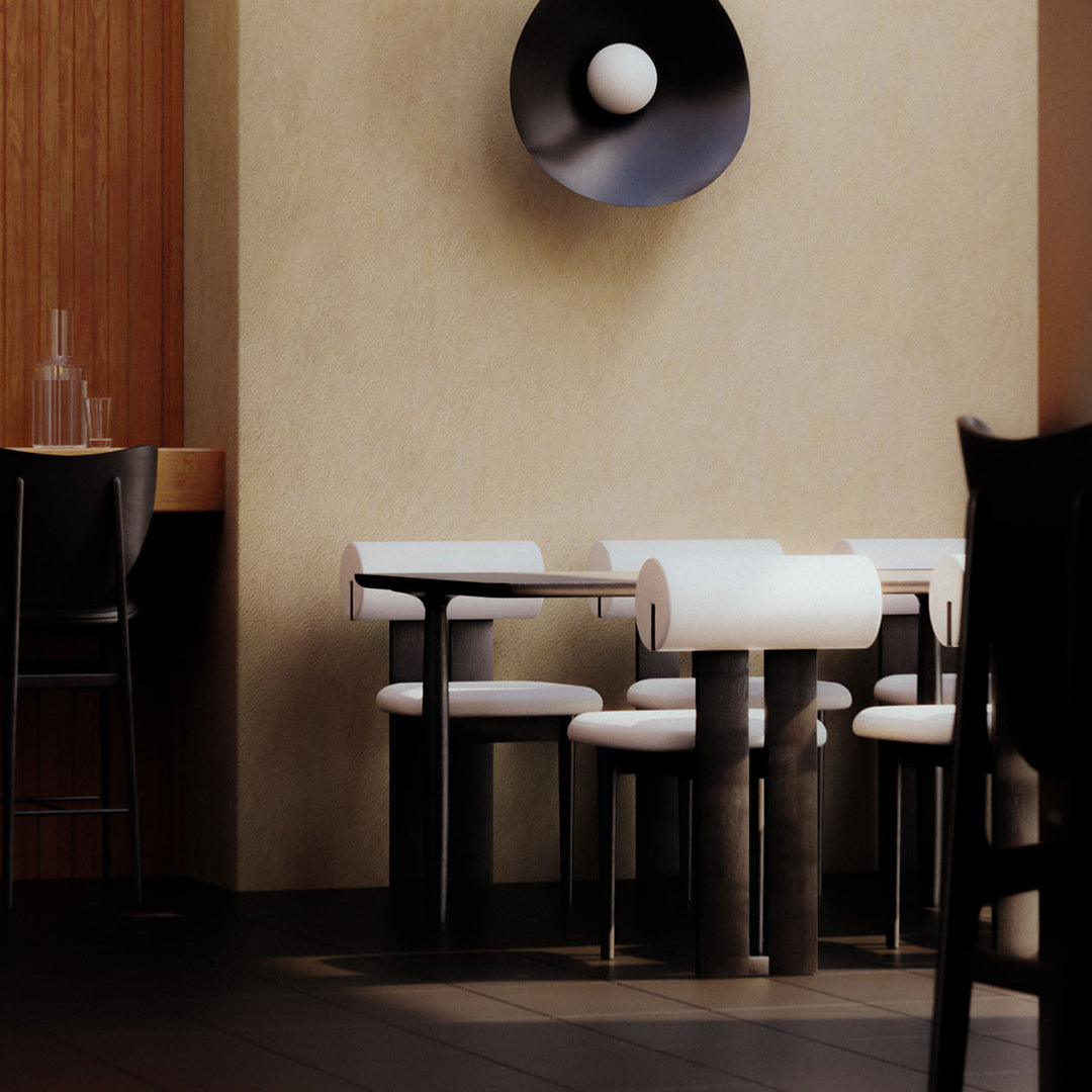 "Modern black and white dining chairs with sleek lines against a warm beige wall and dark flooring."