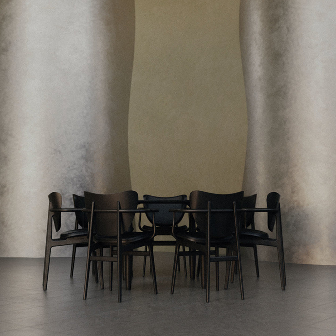 Set of eight black chairs with sleek design against a textured gray wall, showcasing minimalist style and elegance.