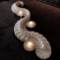 Elegant cream-colored sofa with curved, tufted design, complemented by round wooden tables and soft ambient lighting.