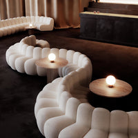 Curved white upholstered seating with soft textures, complemented by warm wooden tables and earthy tones.