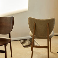 Wooden chairs in dark brown and light beige upholstery, set against a neutral background with geometric patterns on the floor.
