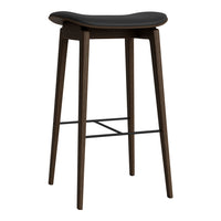Black stool with smooth seat and dark wood legs, featuring a minimalist design and subtle curved pattern.