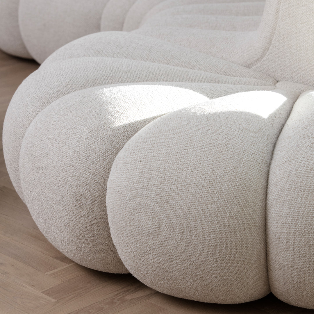 Cream-colored textured fabric with soft, rounded shapes, set against a light wooden floor.