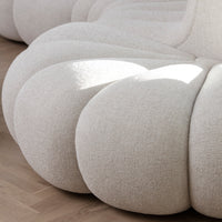 Cream-colored textured fabric with soft, rounded shapes, set against a light wooden floor.