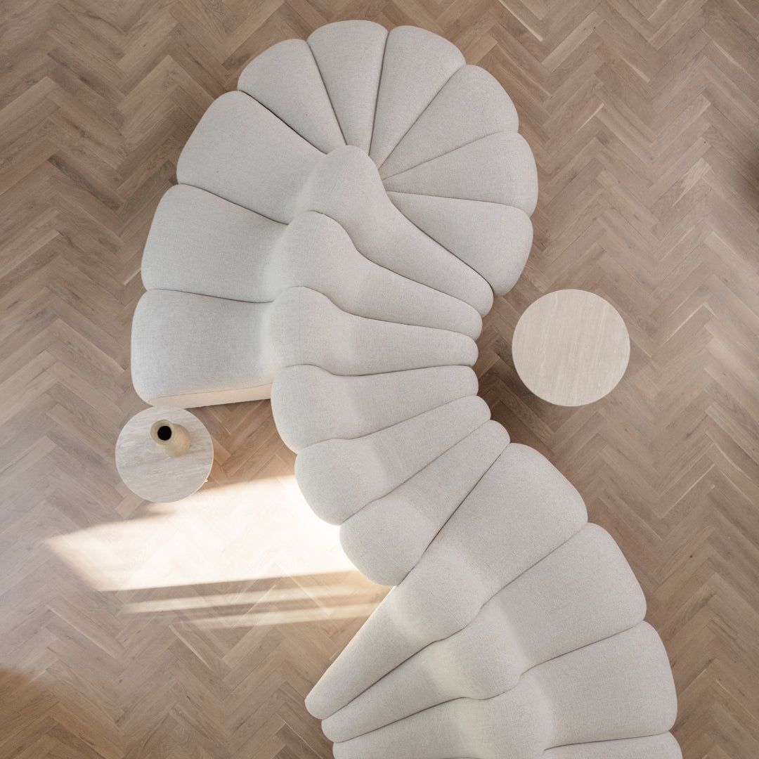 "Curvy beige sofa featuring soft, scalloped patterns on a light wooden floor."