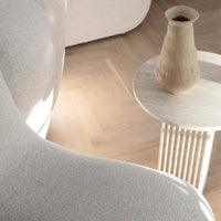 Soft beige fabric sofa with a textured finish, paired with a light wooden table and earthy-toned vase, enhancing warmth.
