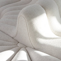 Textured cream upholstery with wave-like patterns, showcasing soft lines and subtle light reflections.