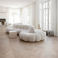Soft cream-colored plush sofa with rounded, cloud-like patterns, set against a light wooden floor.