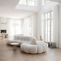 White plush sofa with a rounded, cloud-like shape, featuring soft curves and an elegant, modern design in a bright, airy room.