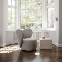 Textured light gray chair with rounded edges, paired with a smooth beige cube in a bright, sunlit room.