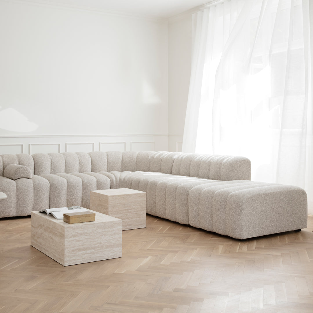 Beige textured sectional sofa with soft, rounded edges, paired with a sleek light wood coffee table in a bright room.