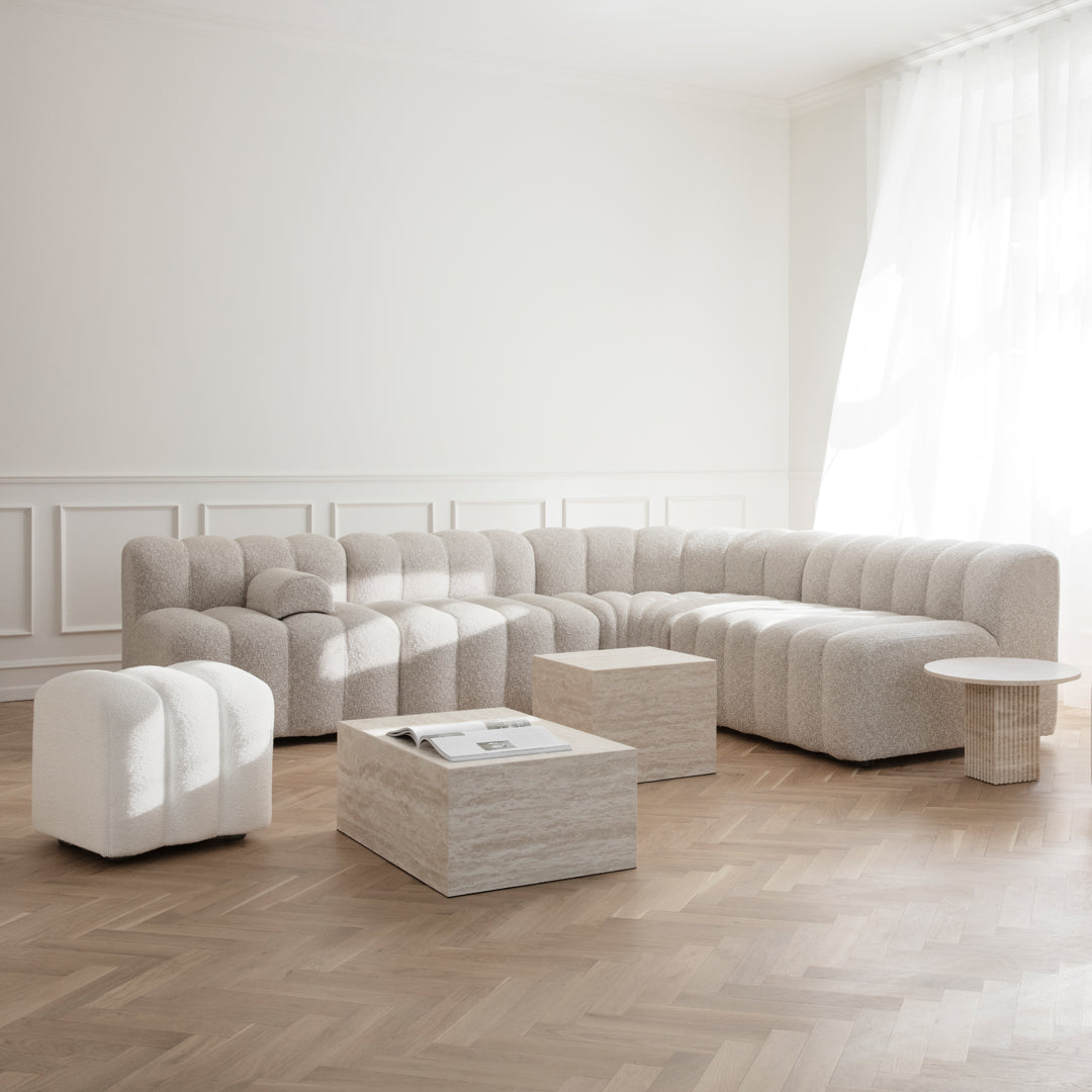 "Soft cream and beige sectional sofa with plush, ribbed texture and minimalist table accents in a bright, airy room."