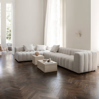 "Elegant white ribbed sofa with plush cushions, set on dark herringbone wood flooring."