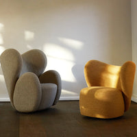 Two modern chairs in soft gray and warm mustard yellow, featuring unique curved shapes and textured fabric.