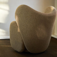 Textured beige accent chair with a smooth, sculptural design, perfect for modern interiors.
