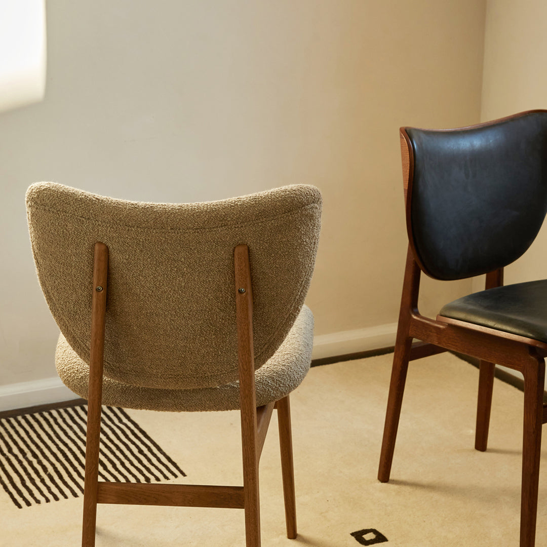 "Neutral grey fabric chair and sleek black leather chair on a light beige carpet with black striped pattern."