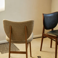 "Neutral grey fabric chair and sleek black leather chair on a light beige carpet with black striped pattern."