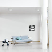 Light grey sofa with a turquoise accent pillow, framed by minimalistic black wall art and white walls.