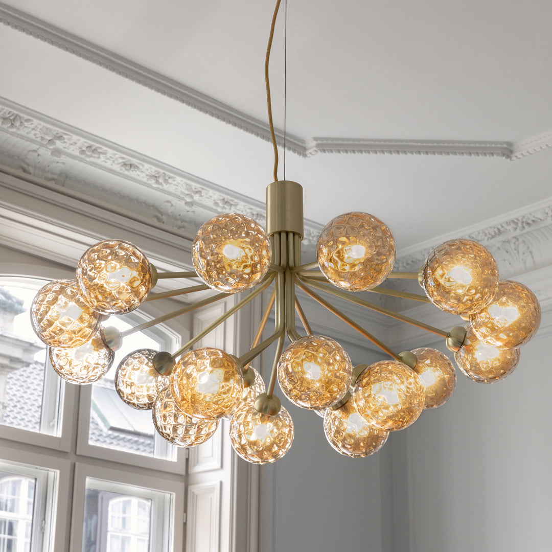 Gold chandelier with textured glass orbs, featuring a sleek design and warm lighting for a modern touch.